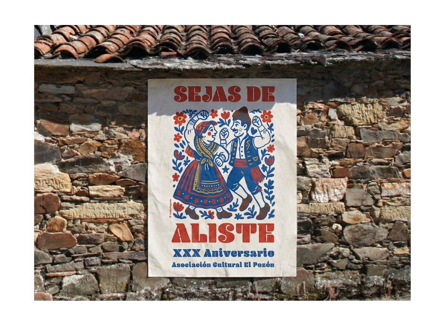 El cartel de las fiestas pegado en una pared de piedra rústica de un pueblo, con tejas de cerámica visibles en la parte superior