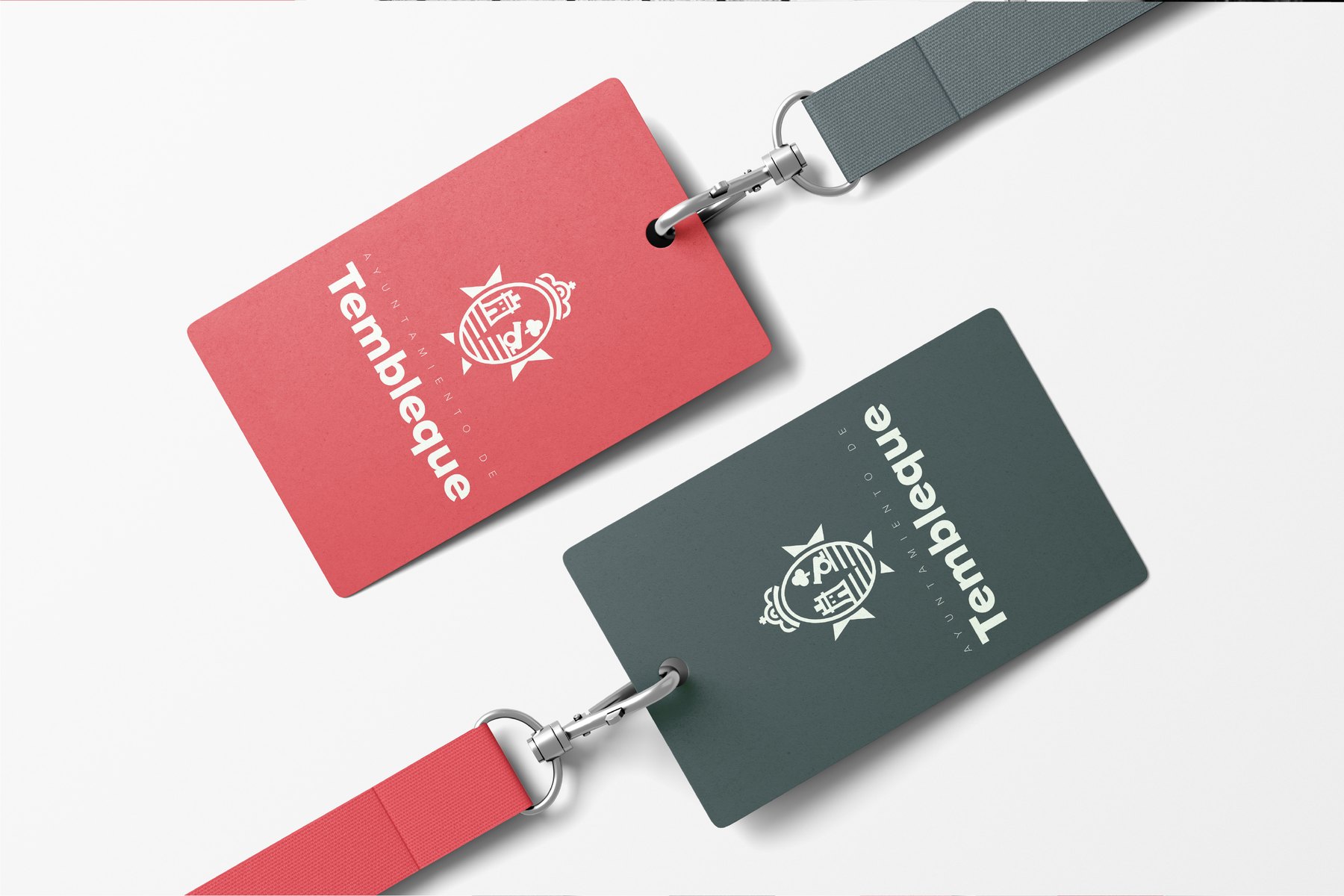 Dos tarjetas plásticas en perspectiva con cordón: la primera roja con cordón carbón, la segunda carbón con cordón rojo, ambas con el escudo en blanco y el texto «Ayuntamiento de Tembleque» en vertical