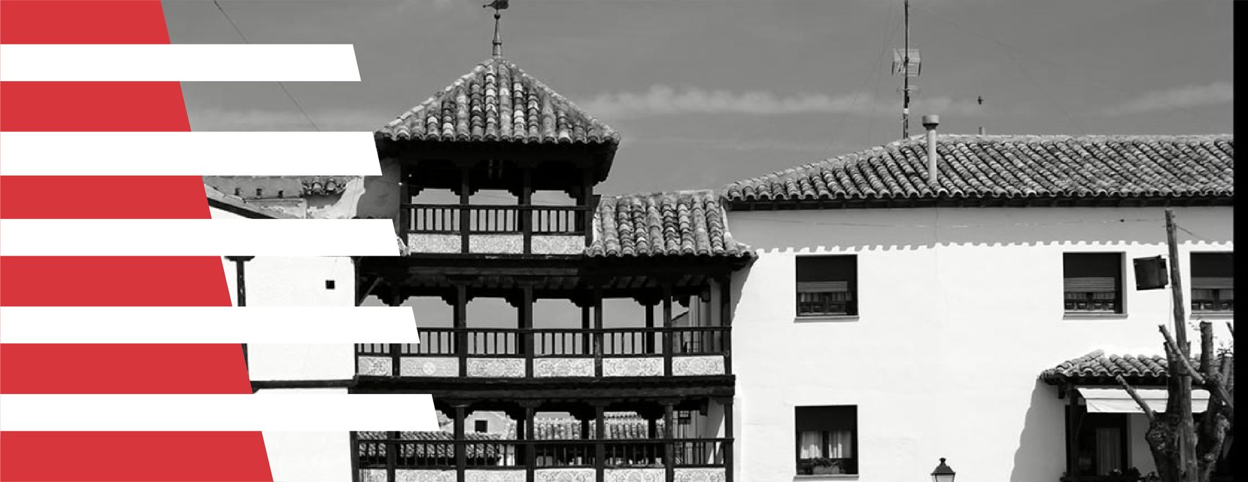 Detalle de banderola vertical roja con damero blanco arquitectónico al pie, sobre fotografía en blanco y negro de fachada de casa toledana con galería de balcones de madera oscura