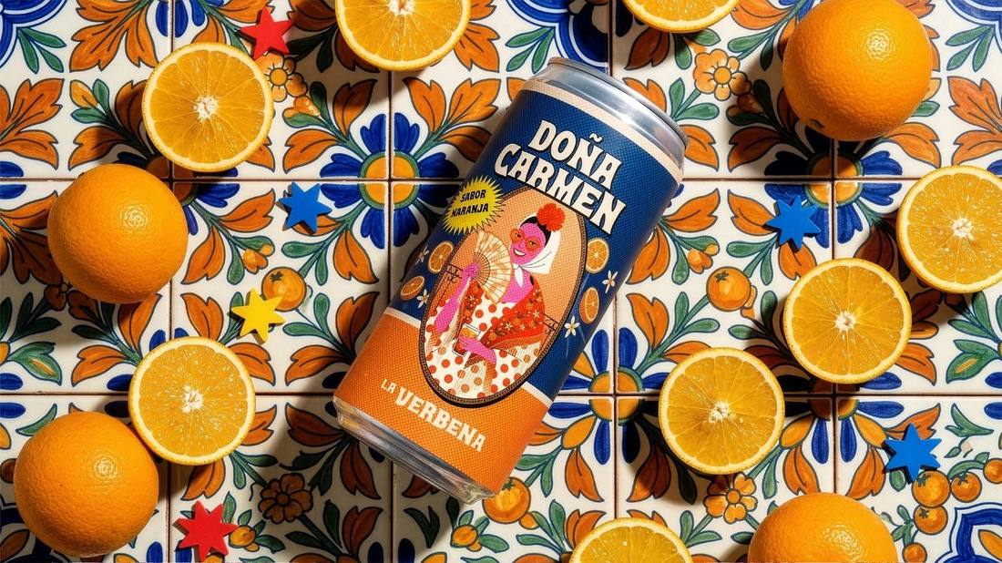 Doña Carmen sabor naranja: lata sobre composición de naranjas partidas y azulejo azul cobalto